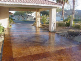 Image of a stamped concrete driveway with dark red and light red stain patterns.