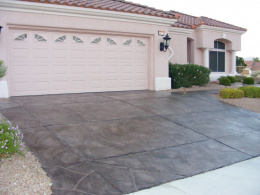 Image of a dark reddish-brown concrete driveway with a wide-cut flagstone overlay.