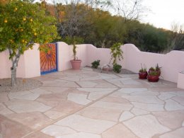 Image of a concrete patio with a wide-cut flagstone overlay and red, tan, and sand-colored stains.