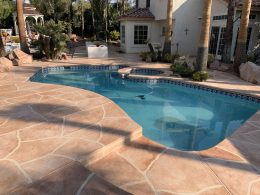 Image of a flagstone overlay concrete poolside with reddish stain.