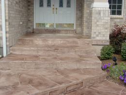 Image of a home entryway with a wide-cute flagstone overlay concrete walkway and steps.