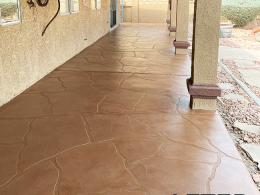 Image of a concrete patio after it has a wide-cut flagstone overlay installed with a reddish stain.