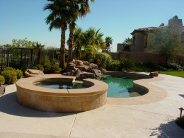 Textured concrete pool deck with accent color and rock features in Las Vegas.