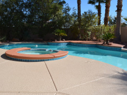 Textured concrete pool deck with accent color on spa and platform in Las Vegas.